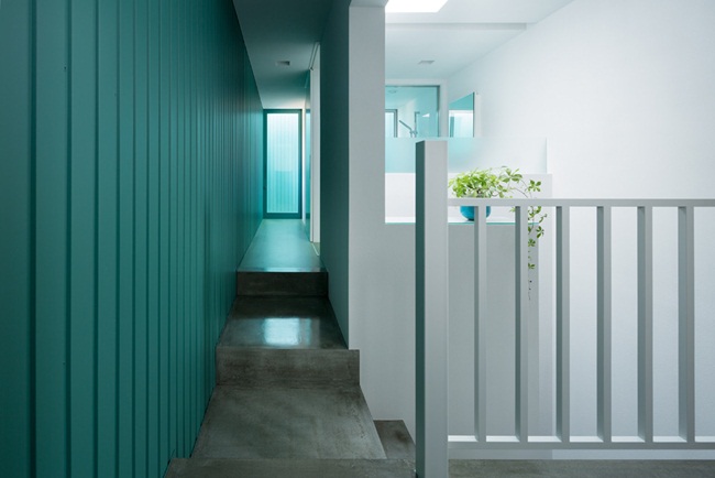 Ở tay phải, hành lang màu xanh tạo cảm giác sạch sẽ dẫn đến phòng vệ sinh, phòng tắm gần đó.