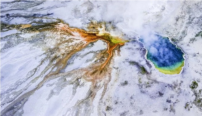Lửa và băng: Bức ảnh chụp từ Công viên Quốc gia Yellowstone ở Mỹ. Bề mặt băng giá phủ lên những mảng màu sắc rực rỡ khi nước lưu huỳnh nóng chảy qua tuyết. 
