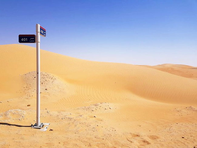 Đây là biển báo đường phố trên sa mạc, giao lộ của 2 làn đường trên cát.
