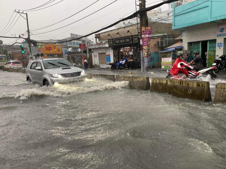 Sóng nước cuồn cuộn, người dân TPHCM “bơi” trên đường sau trận mưa lớn